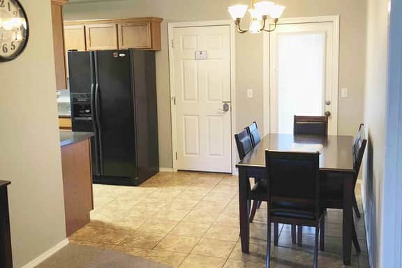 The dining area has a table and seating for six and is adjacent to the living room and kitchen.  The doors to the backyard and garage/gym are pictured.